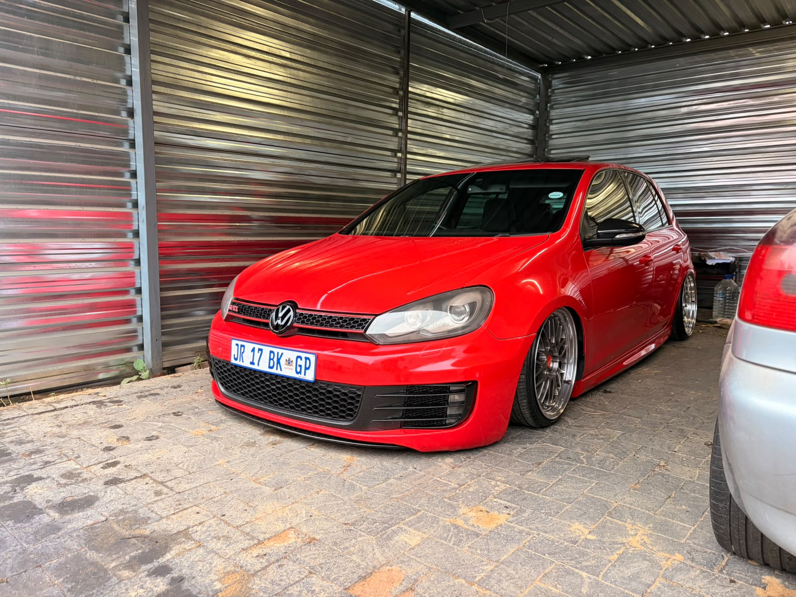 Red Volkswagen Golf GTI on polished split-rim wheels after a touchless wash